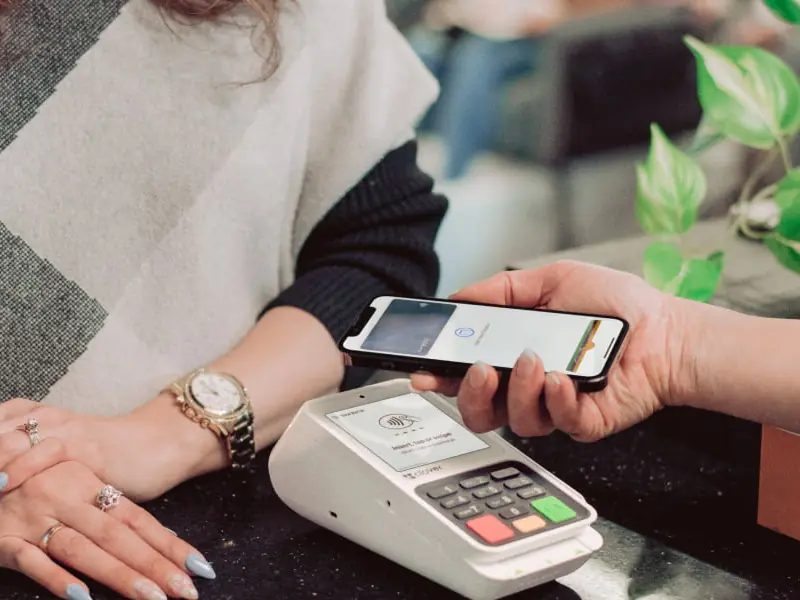 A customer taps a phone on a Clover Compact at a boutique counter