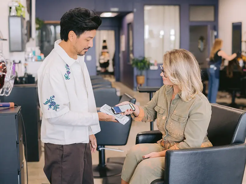 A stylist takes a card payment on a Clover Flex from a client in the salon chair