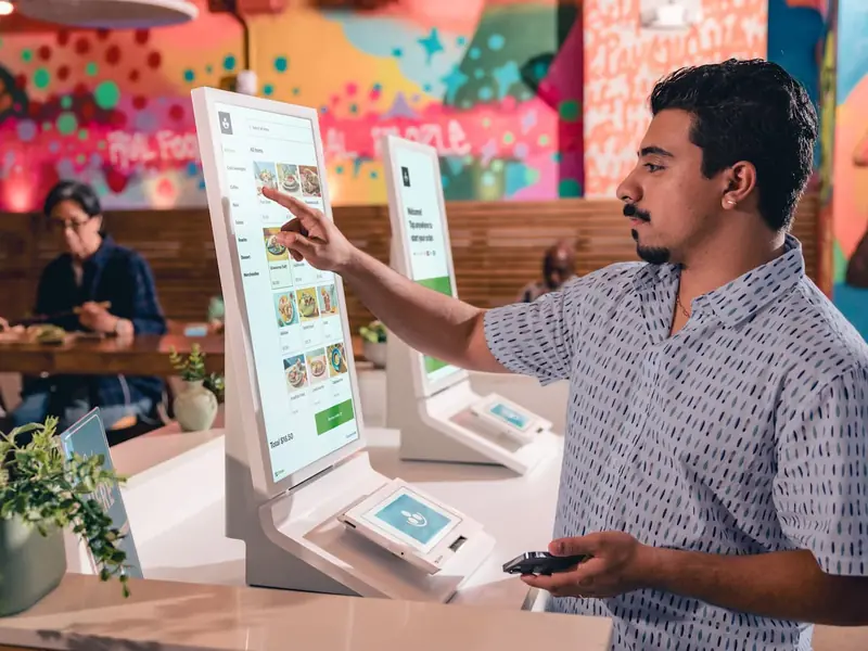 A customer orders on a Clover Kiosk in a fast-casual restaurant