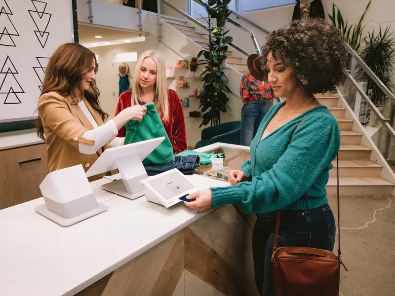 A shopper pays at a Clover Station Duo at a bright boutique counter