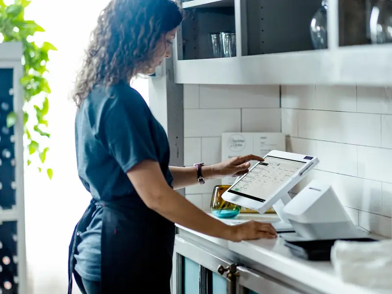 A restaurant server enters an order on a Clover Station Solo at a service station